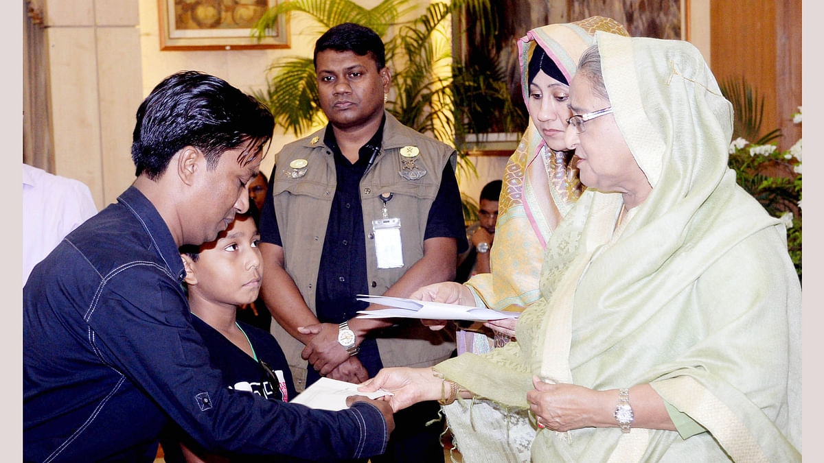 Awami League president and prime minister Sheikh Hasina hands over financial assistance to the family members of those killed and injured in the August 21 grenade attack, at Ganabhaban on Tuesday. Photo: PID
