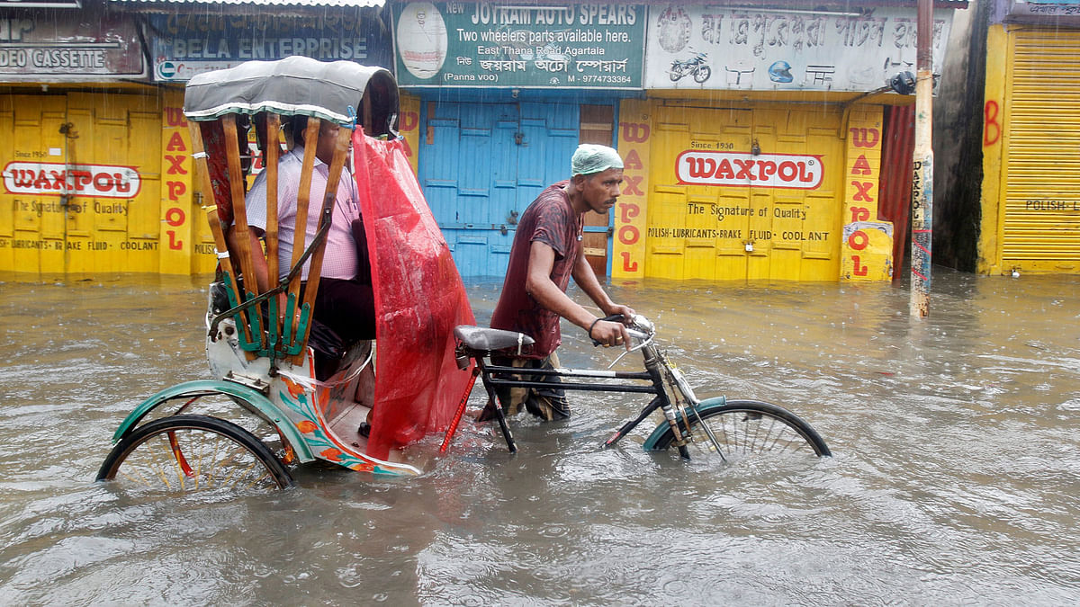 A man paddles his rickshaw as he helps a passenger wade through a water-logged street during heavy rains in Agartala, India on 18 May. Photo: Reuters