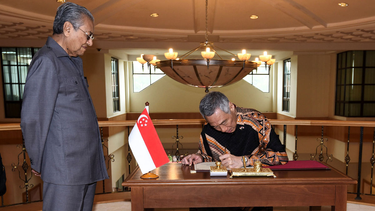 Singapore’s prime minister Lee Hsien Loong signs a guestbook next to Malaysia’s prime minister Mahathir Mohamad prior to their private meeting at the Perdana Leadership Foundation in Putrajaya, Malaysia on 19 May. Photo: Reuters