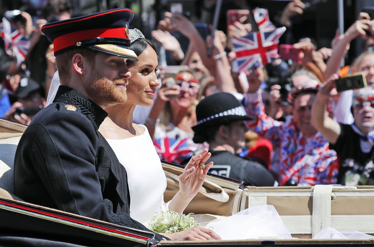 Britain`s Prince Harry, Duke of Sussex and his wife Meghan, Duchess of Sussex travel in the Ascot Landau Carriage during their carriage procession on Castle Hill outside Windsor Castle in Windsor, on 19 May, 2018 after their wedding ceremony. Photo: AFP