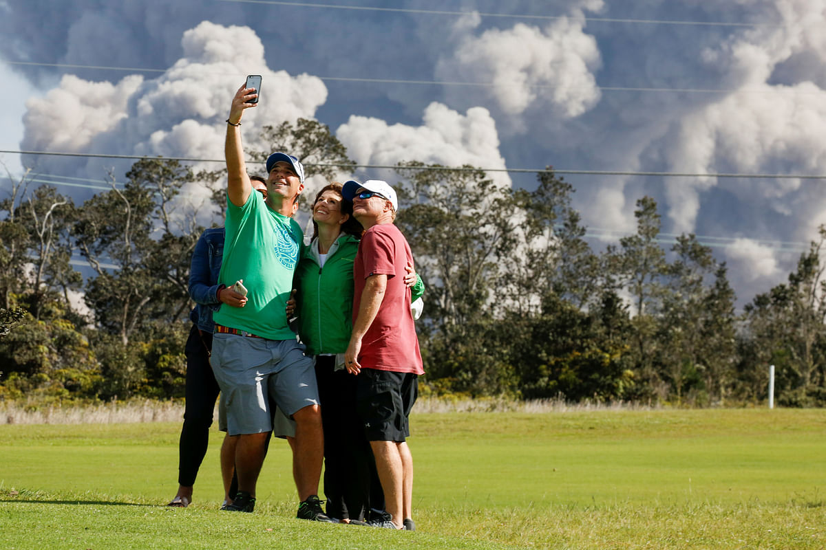 Sean Bezecny, 46, of Houston, Texas, takes a photo with his family and friends as ash erupts from the Halemaumau Crater near the community of Volcano during ongoing eruptions of the Kilauea Volcano in Hawaii, US on 19 May. Photo: Reuters