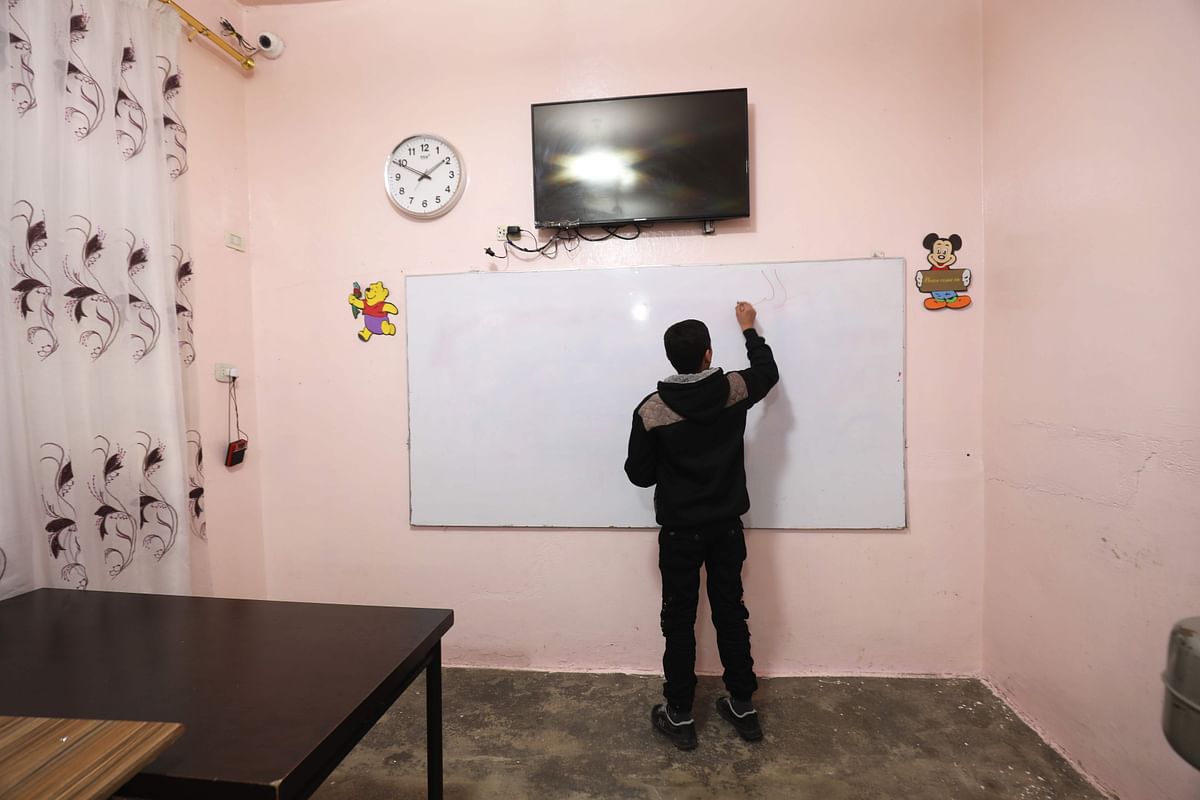 An adolescent boy writes on a white board at the `Hori` rehabilitation centre run by Kurds in Tal Maarouf, in Syria on 11 February 2018. Photo: AFP