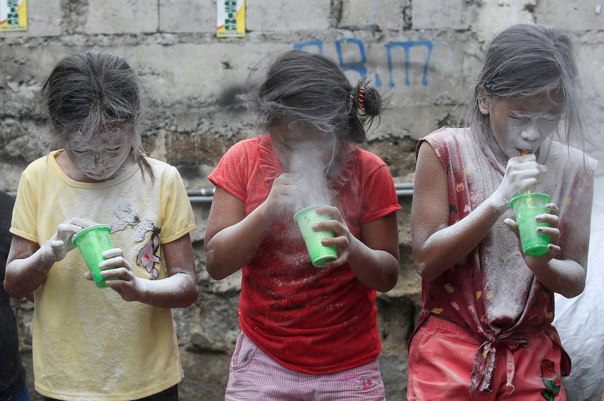 Girls` faces are covered by white powder after blowing it, at a town fiesta parlour game, in celebration of patron saint Santa Rita de Cascia in Baclaran, Paranaque City, Metro Manila, Philippines 20 May 2018. Photo: Reuters