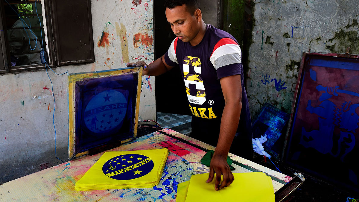 This photograph taken on 17 May 2018 shows a Bangladeshi worker using a silk-screen for printing a Brazil flag in Narayanganj, on the outskirts of Dhaka, ahead of the 2018 football World Cup. Photo: AFP