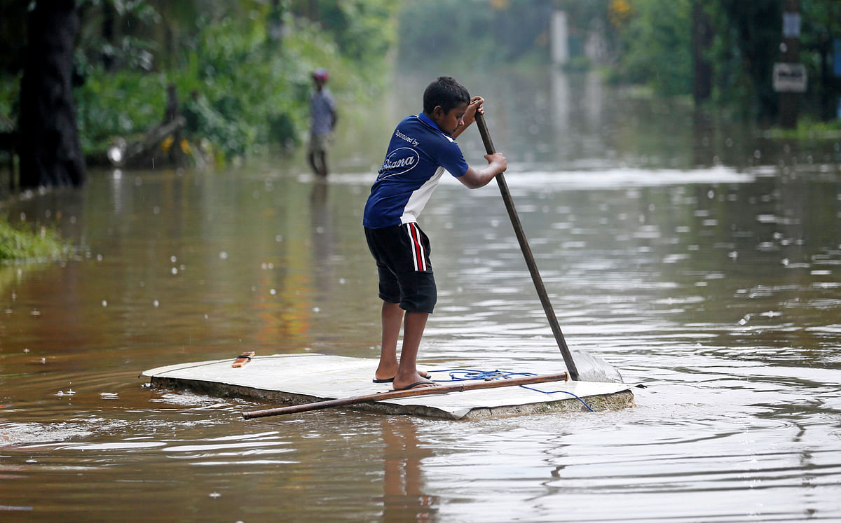A boy paddles as he floats on a foam board on a flooded road in the heavy rains in Biyagama, Sri Lanka on 23 May. Photo: Reuters