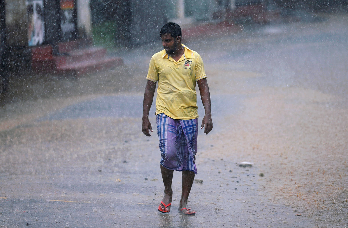 A man walks along a road in the heavy rains in Malwana, Sri Lanka on 23 May 2018. Photo: Reuter