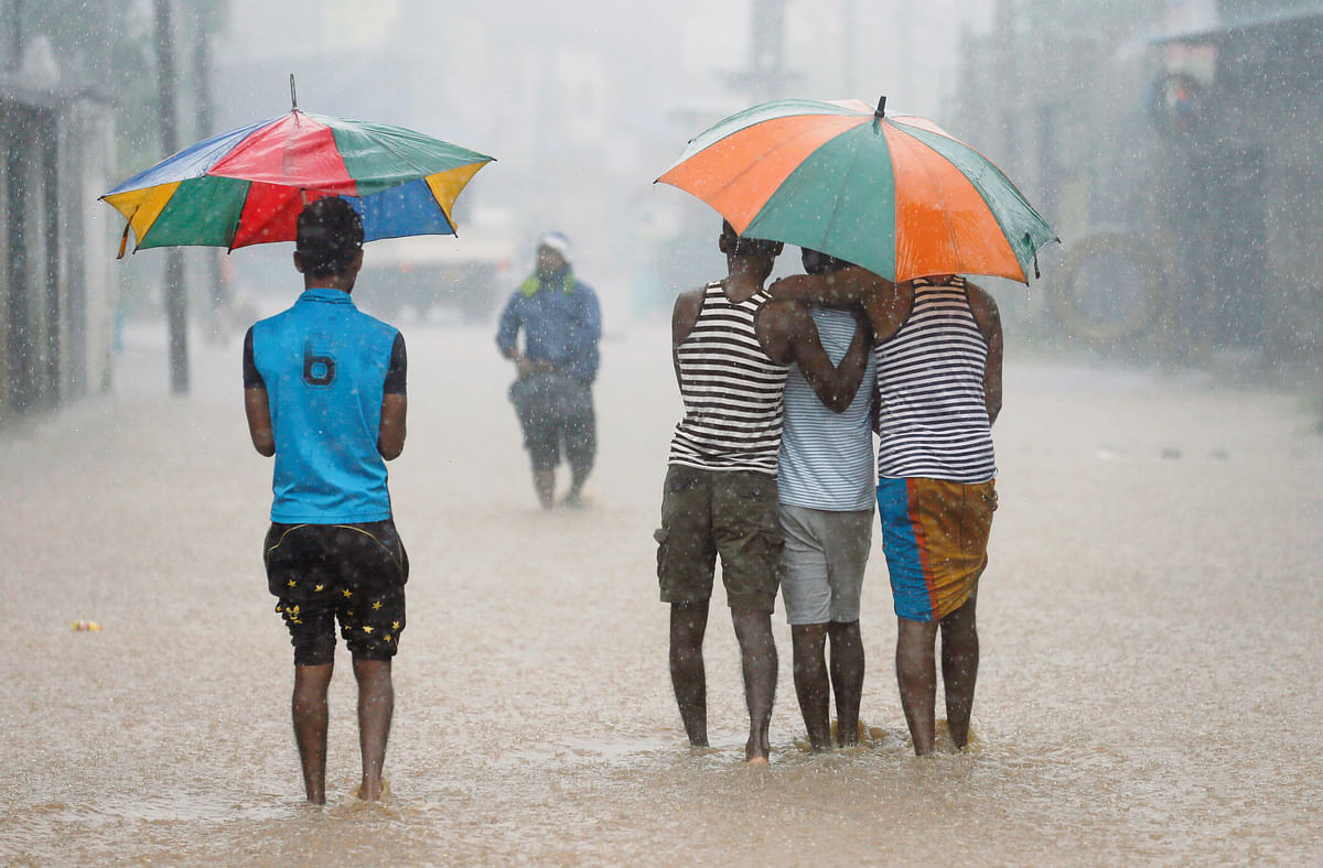 Men walk along a flooded road in the heavyrains in Malwana, Sri Lanka on 23 May 2018. Photo: Reuters