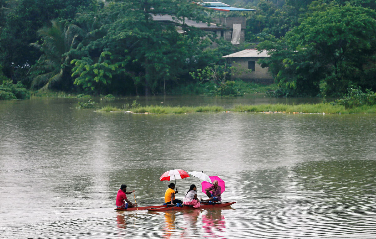 Villagers travel in a boat to cross the towns near a flooded road in Malwana, Sri Lanka on 23 May 2018. Photo: Reuters