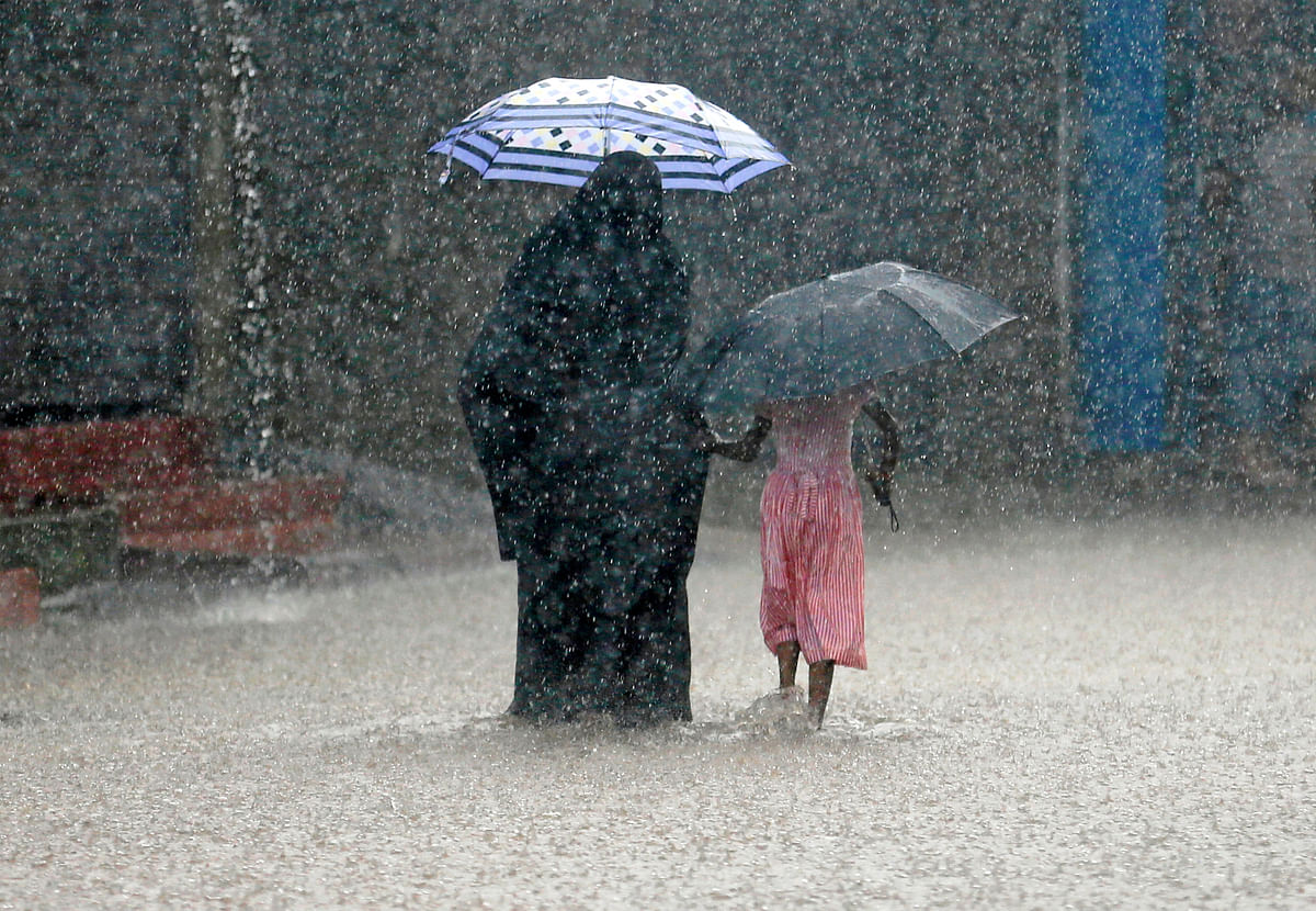 A woman walks with a girl along a flooded road in the heavy rains in Malwana, Sri Lanka on 23 May. Photo: Reuters