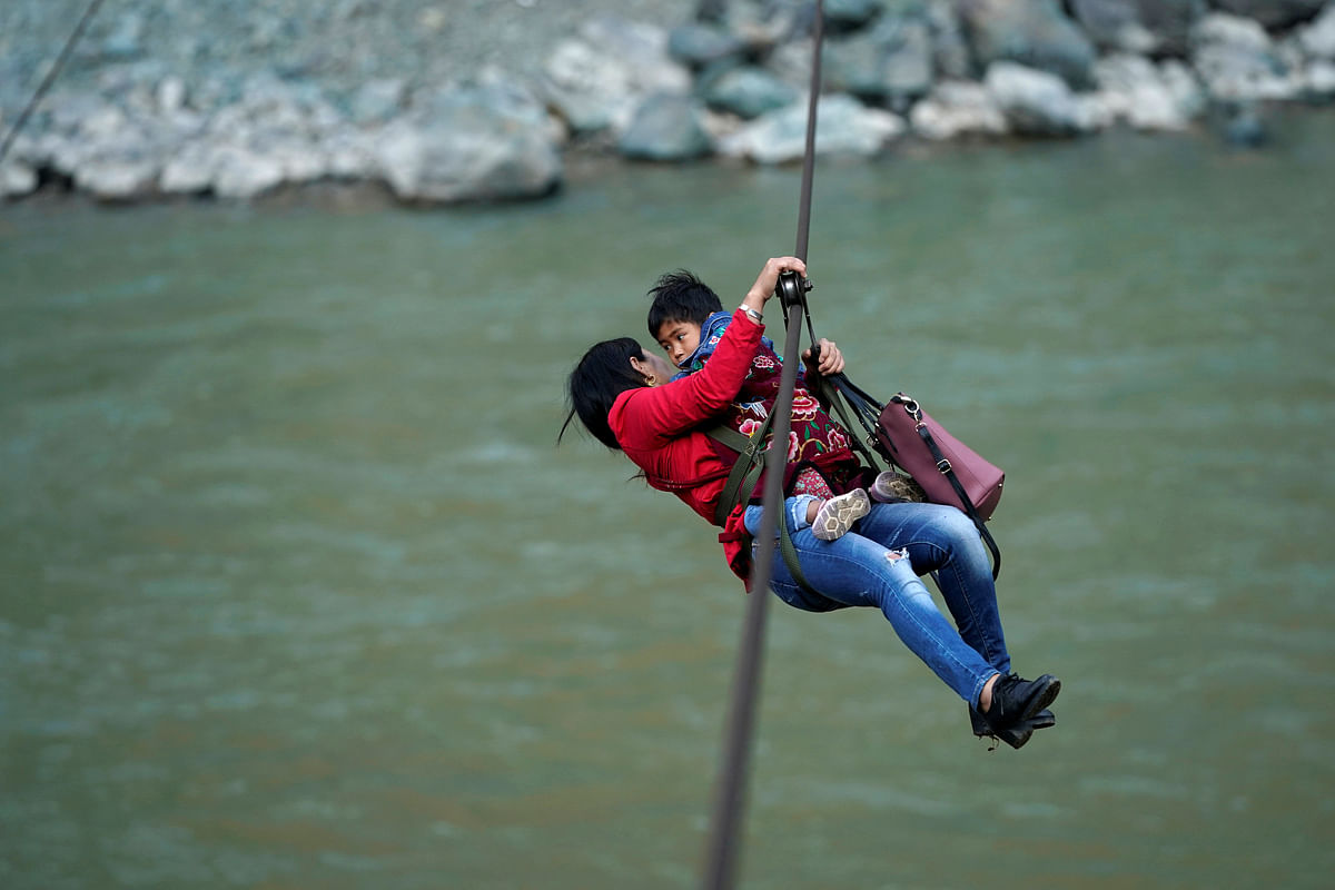 Cha Huilan, a 40-year old Lisu woman, and her daughter leave Lazimi village with a zipline across the Nu River in Nujiang Lisu Autonomous Prefecture in Yunnan province, China on 24 March. Photo: Reuters