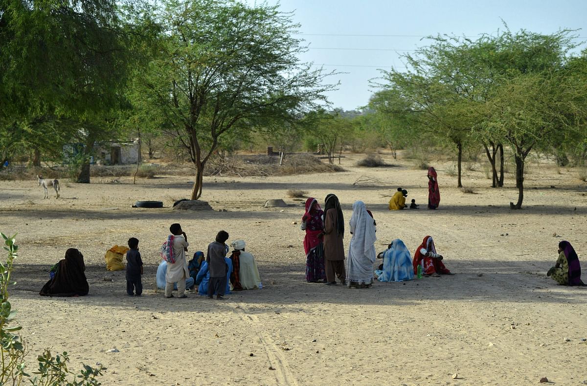 Pakistani villagers sit under trees on a hot summer day at Islamkot in Tharparkar district in Sindh province on 22 May 2018. Photo: AFP