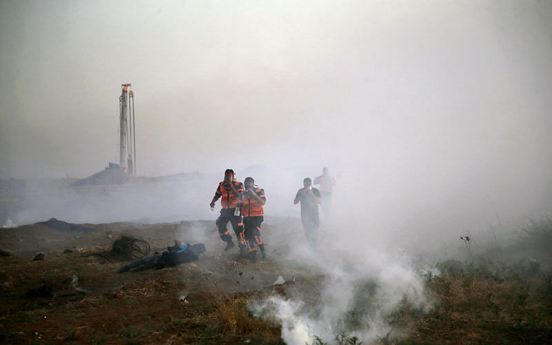 Palestinian paramedics run in the smoke billowing from tear gas shot by Isreali forces during a demonstration along the border between Israel and the Gaza strip, east of Gaza City, on 25 May 2018. AFP