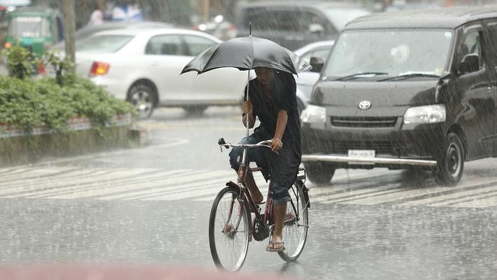 After a hot day a heavy rain in the afternoon comforted the people of the city. Holding an umbrella in one hand a man is seen to hold the bicycle handlebar with other hand. The photo was taken by Sumon Yusuf from Gulshan 1 Circle area, Dhaka on 25 May