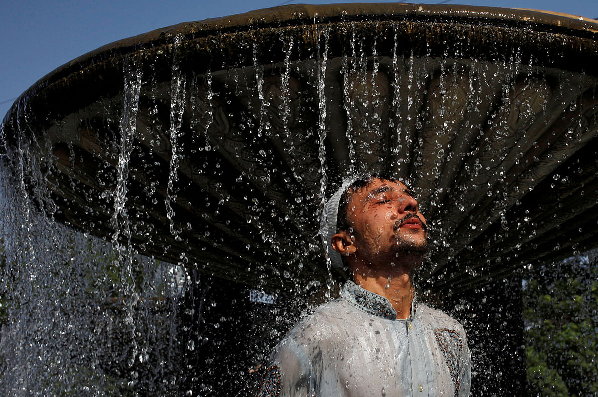 A man cools off from the heat wave, as he takes a shower at a water fountain along a road in Karachi, Pakistan on 25 May 2018. Photo: Reuters