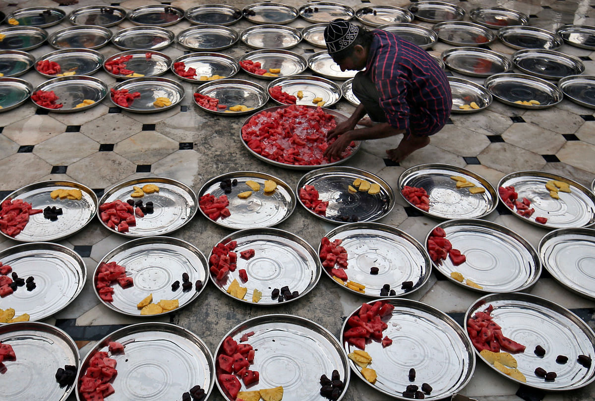 A Muslim man prepares plates of food for Iftar (breaking fast) meals inside a mosque during the holy fasting month of Ramadan in Ahmedabad, India on 27 May. Photo: Reuters