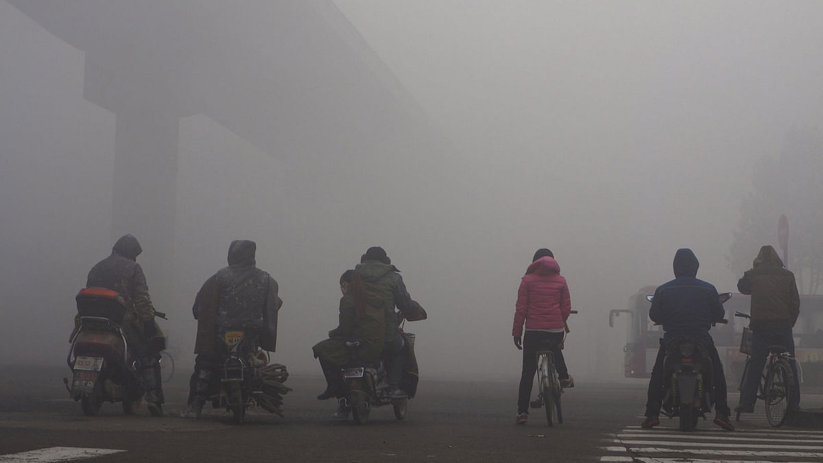Residents on their bicycles and electric bikes wait for the traffic at an intersection amid heavy smog in Shijiazhuang, Hebei province, China, on 10 December 2015. Reuters File Photo