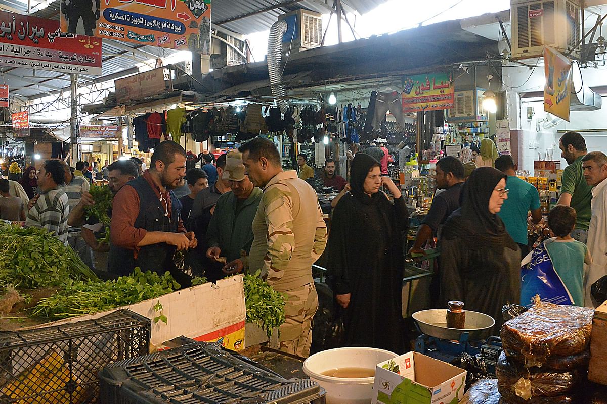 Iraqi men and women buy food in an open air market after breaking the fast during the holy month of Ramadan in Mosul on 24 May 2018. Photo: AFP