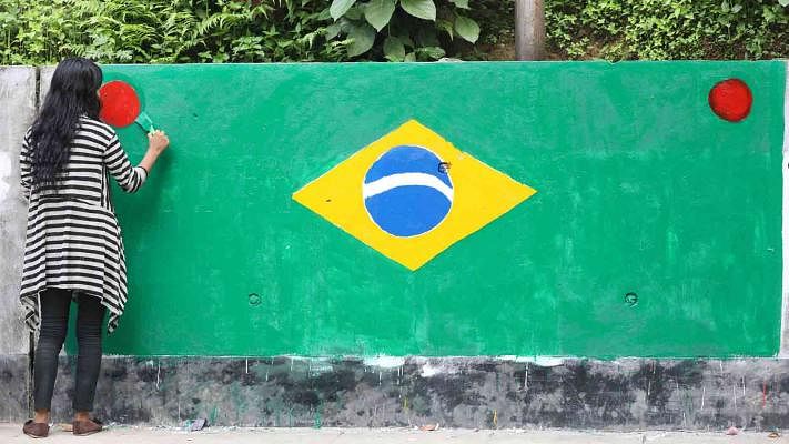 A Brazil fan paints Brazil`s flag on the wall in CRB area in Chattogram. Photo: Sourav Dash