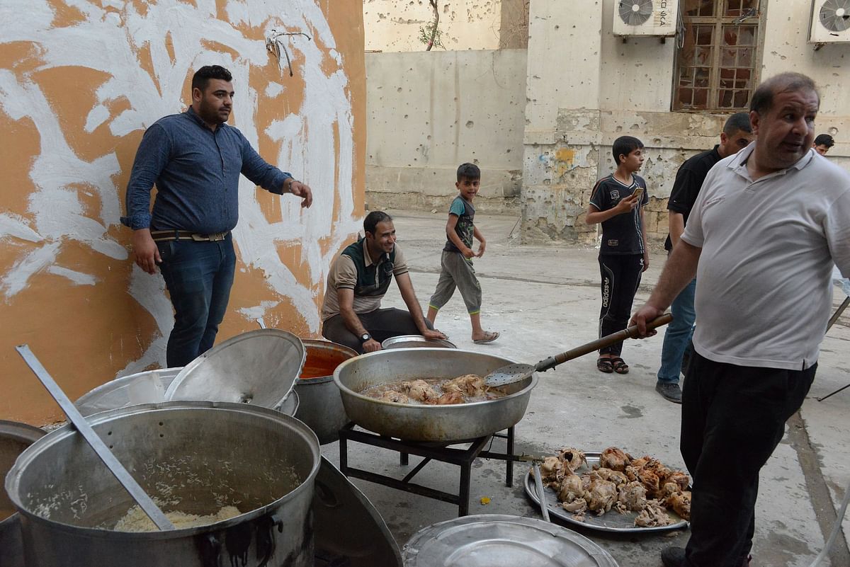Iraqi men prepare food for Iftar, the sunset meal that breaks the daytime fast, which a charity organisation in Mosul distributes to those in need during the holy fasting month of Ramadan in the northern Iraqi city on 21 May 2018. Photo: AFP