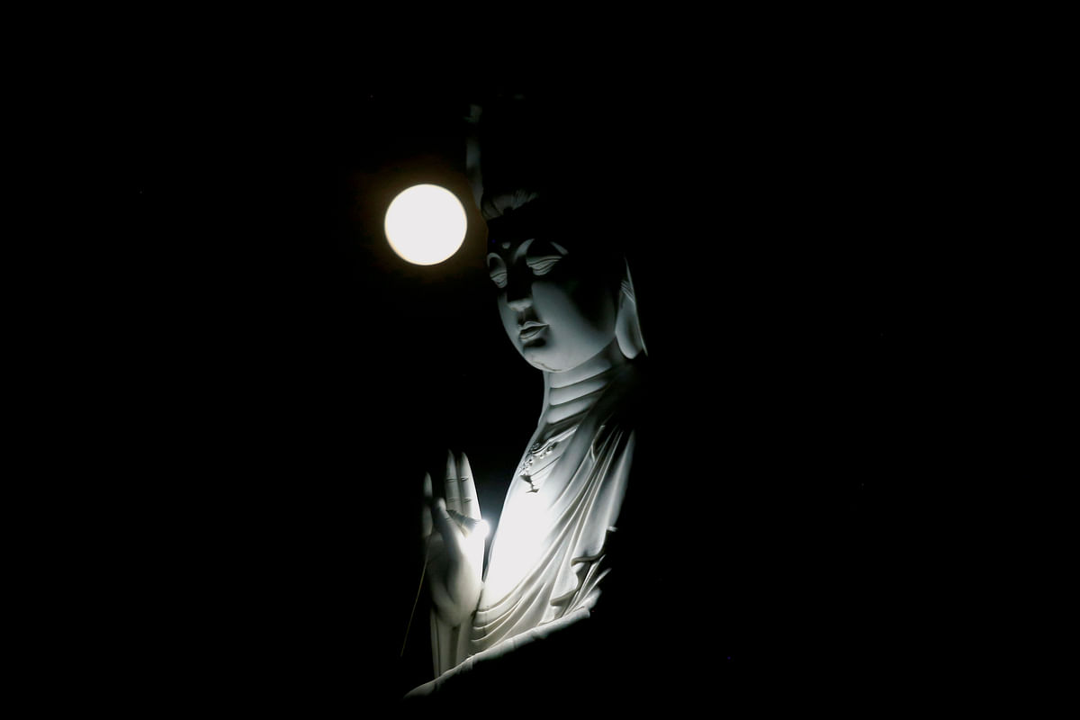 The full moon is seen behind a Buddha statue during the Vesak Day celebrations at Duoc Thuong pagoda in Hanoi, Vietnam on 29 May 2018. Photo: Reuters