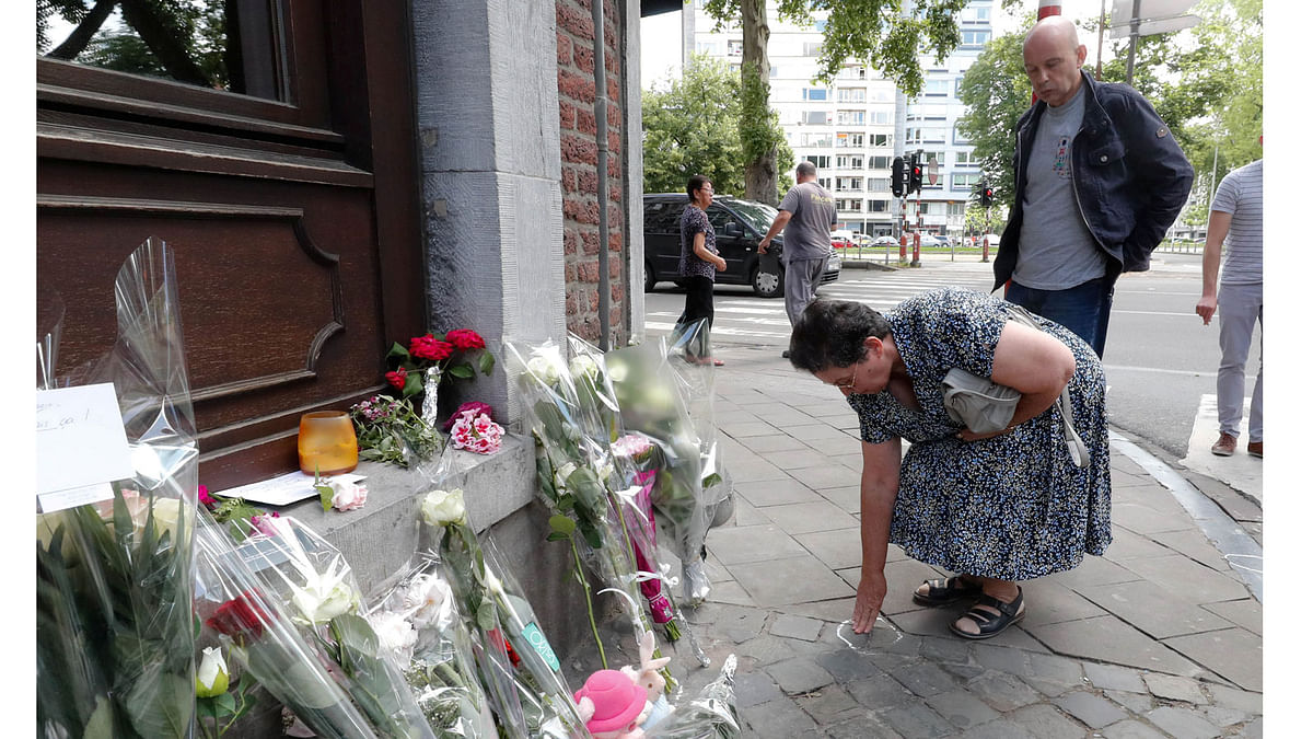 Bernadette Hennart, mother of late police officer Soraya Belkacemi, accompanied by her son Kamel Belkacemi, touches the pavement where her daughter was killed on 29 May during a shooting in Liege, Belgium on 30 May 2018. Photo: Reuters