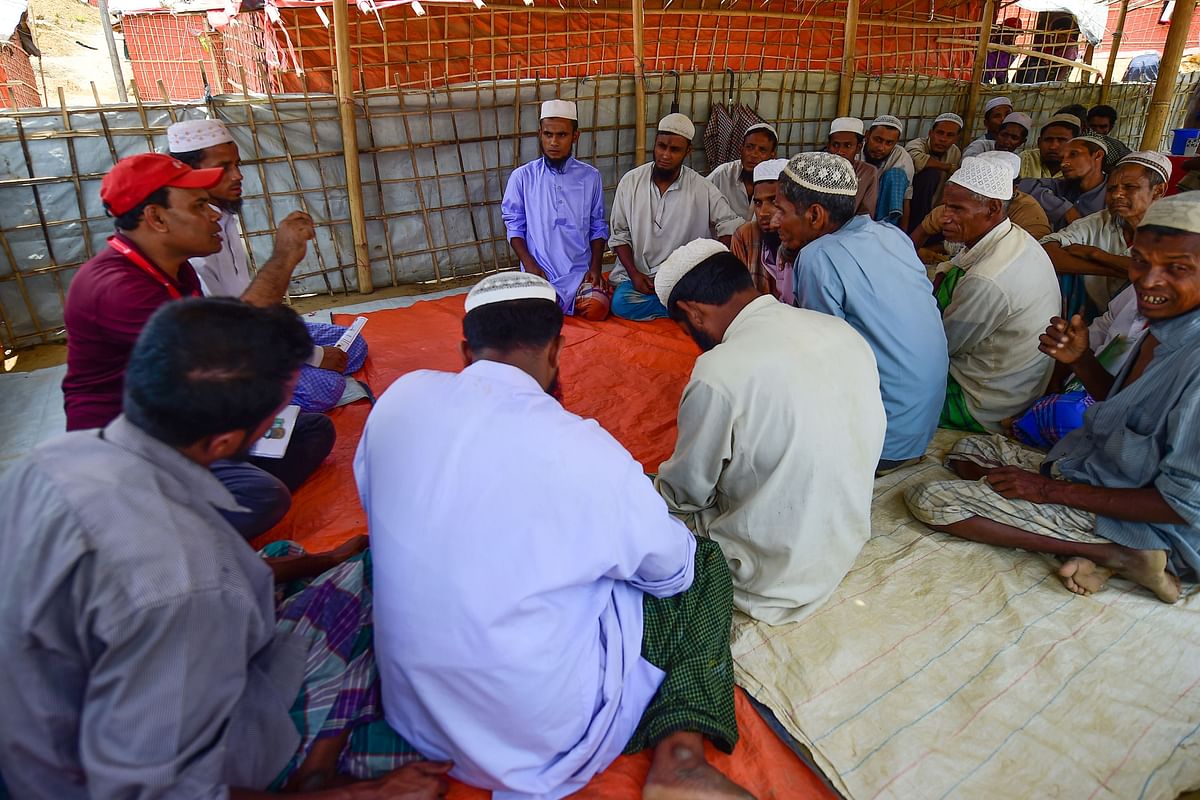 In this photograph taken on 10 May 2018, an NGO worker (L) talks with a Muslim cleric and other members of the congregation about preparations for the upcoming monsoon season in Kutupalong refugee camp in Ukhia. Photo: AFP