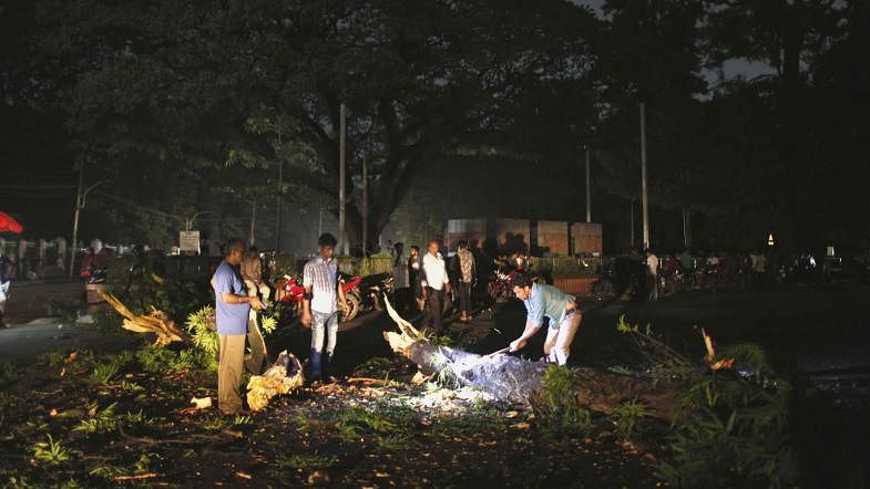The road in front of the residence of the vice chancellor of Dhaka University was blocked for a while as a tree fell during a storm on Wednesday evening. The road is being cleared for use under torchlight due to power outage. Photo: Sumon Yusuf.