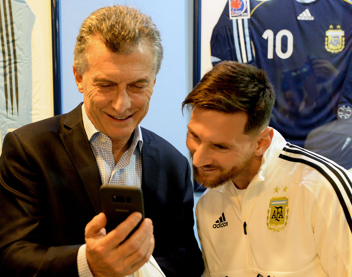 Argentine president Mauricio Macri (L) looking at his cellphone next to Argentinian national football team forward Lionel Messi, at the Argentine Football Association (AFA) training facilities in Ezeiza, Buenos Aires on May 30, 2018 where the president arrived to bid farewell to the team before it travels to Barcelona for the last stage of preparation ahead of the FIFA World Cup 2018. Photo: Reuters.