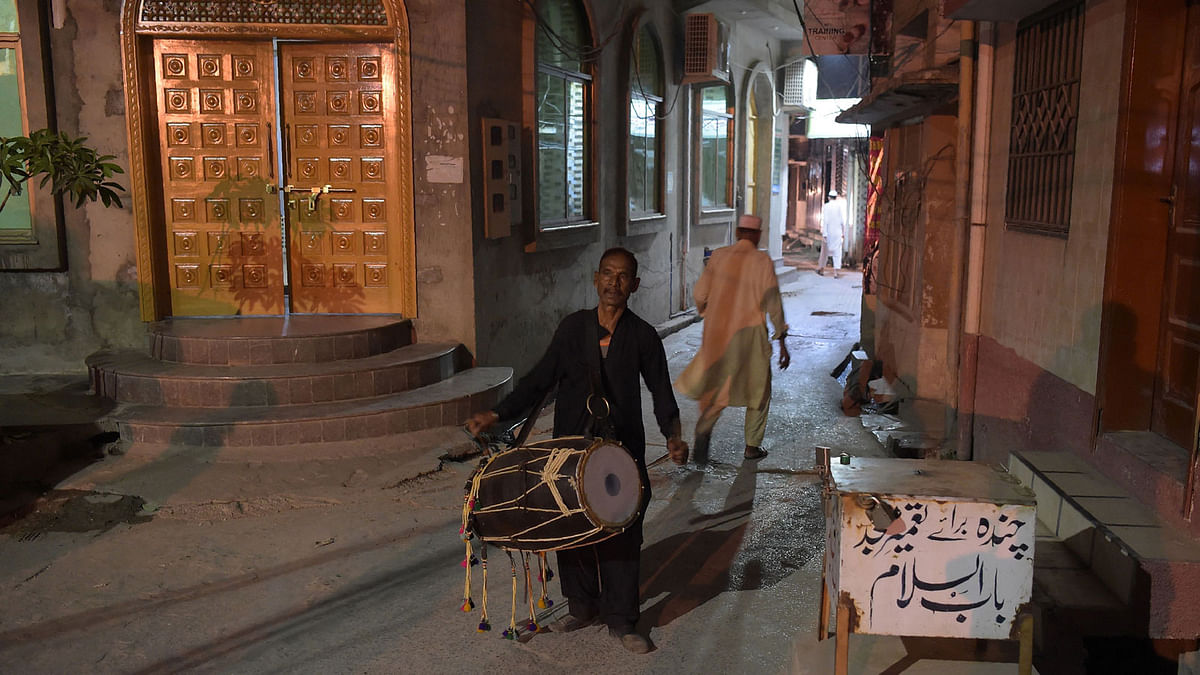 A Pakistani man Lal Hussain (C), 66, `Ramadan drummer` beats his drum as he makes calls at doors `wake up and eat your sehri morning meal` before thier fasting during Ramadan at Bani, an old residential area, in Rawalpindi on 30 May 2018. Photo: AFP
