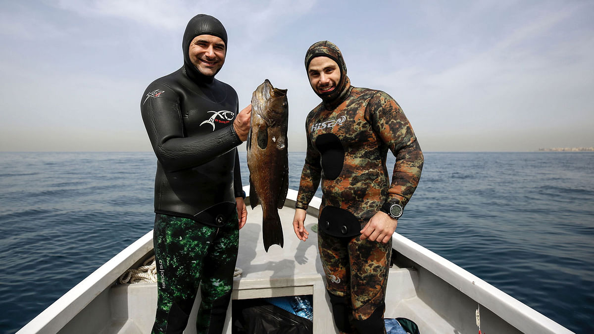 Lebanese freedivers Rachid Zock (L) and Jamal Hilal hold a Grouper fish that they hunted with a speargun, off of the coast of Qalamun in northern Lebanon, on 4 March 2018. AFP