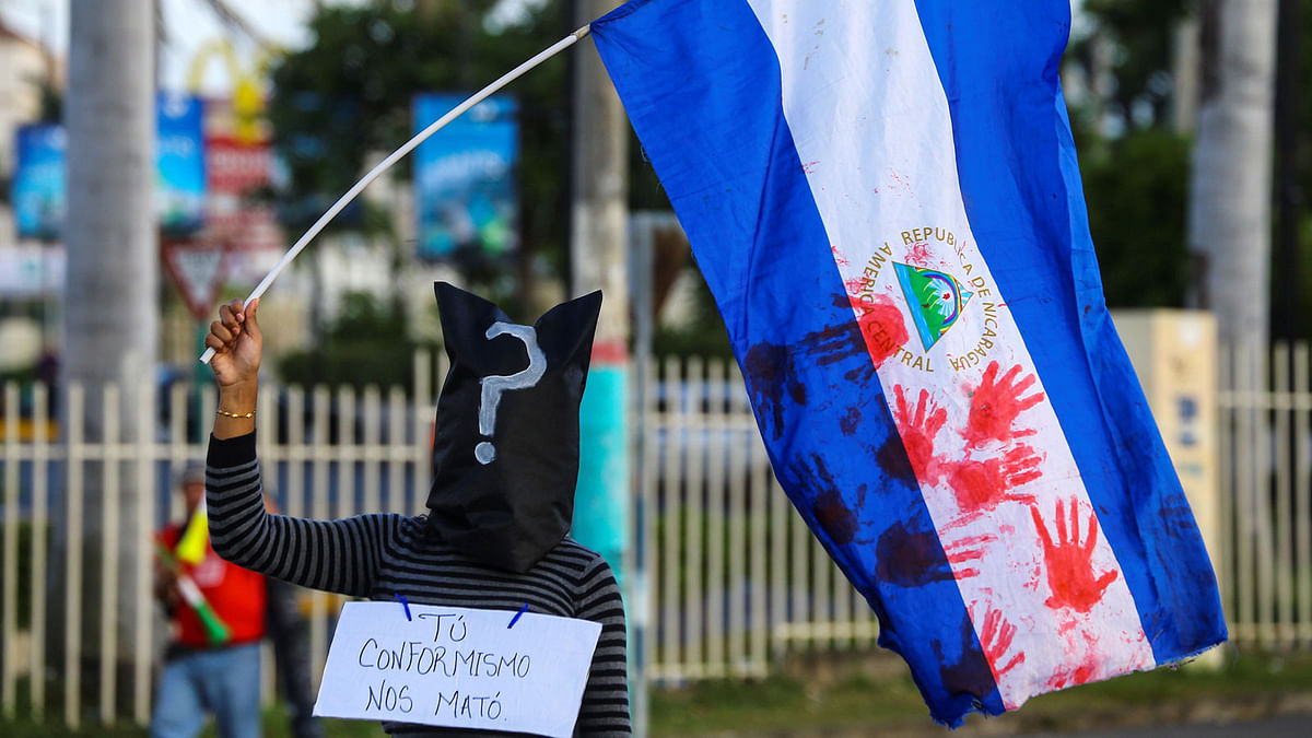 A masked demonstrator holds a national flag in support of teenagers who have died in recent protests against Nicaraguan president Daniel Ortega`s government in in Masaya, Nicaragua on 30 may. Photo: Reuters
