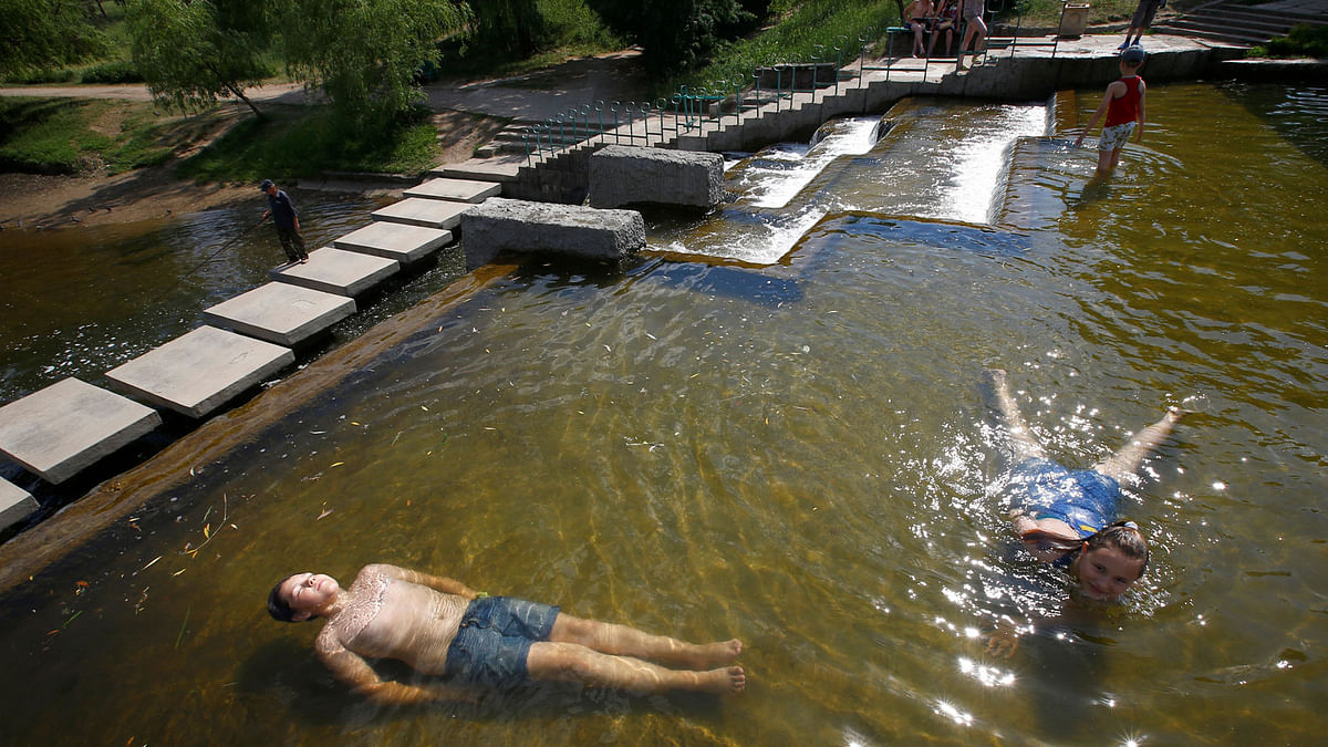 Children cool down in a channel during a very hot day in Minsk, Belarus on 30 May 2018. Photo: Reuters