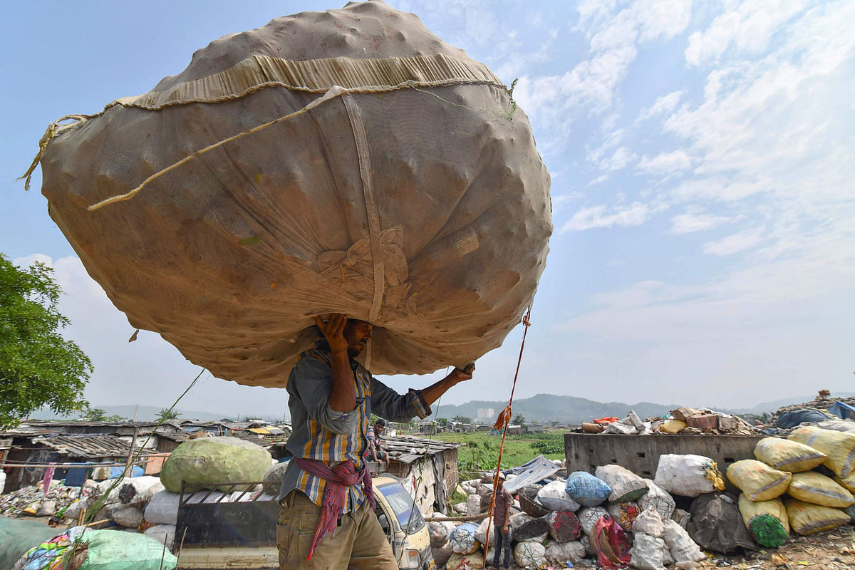 An Indian labourer carries a sack of plastic bottles on his head near one of the largest disposal sites in north-east India, ahead of the `World Environment Day` in Boragaon area of Guwahati on 4 June 2018. Photo: AFP