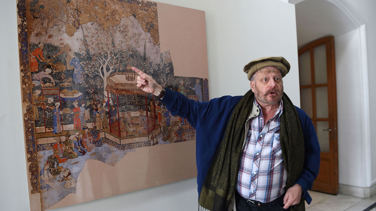 In this photograph taken on 15 April 2018, American historian Michael Barry gestures during an interview with AFP alongside artwork displayed at the `King Babur`s Kabul, Cradle of the Mughal Empire` exhibition at the Bagh-e-Babur Garden in the Afghan capital Kabul. Photo: AFP
