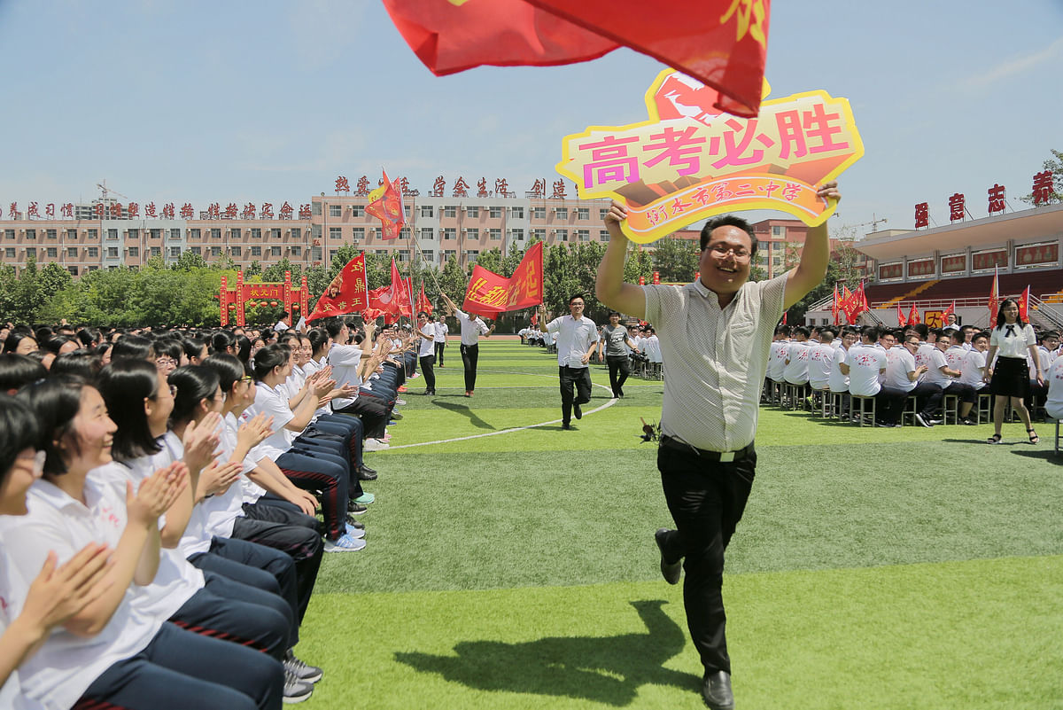 Teachers run with signs as they cheer for students at a rally ahead of the annual national college entrance examination, or `gaokao`, at a high school in Hengshui, Hebei province, China on 24 May 2018. Photo: Reuters