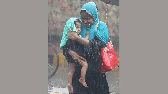 A mother tries to save her daughter while on road in a sudden rain. Atish Dipankar Road, Basabo, Dhaka, 4 June. Photo: Abdus Salam