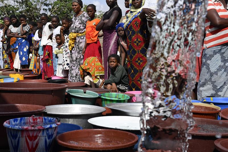 A worker of the National Office of Drinking Water (ONEP) distributes water to the population on June 2, 2018 in a district of Bouake, central Ivory Coast, where the largest dam of the `Societe de Distribution de l`Eau de la Cote d`Ivoire` (SODECI - Water Distribution Company of Ivory Coast) has dried for several weeks. Photo: AFP