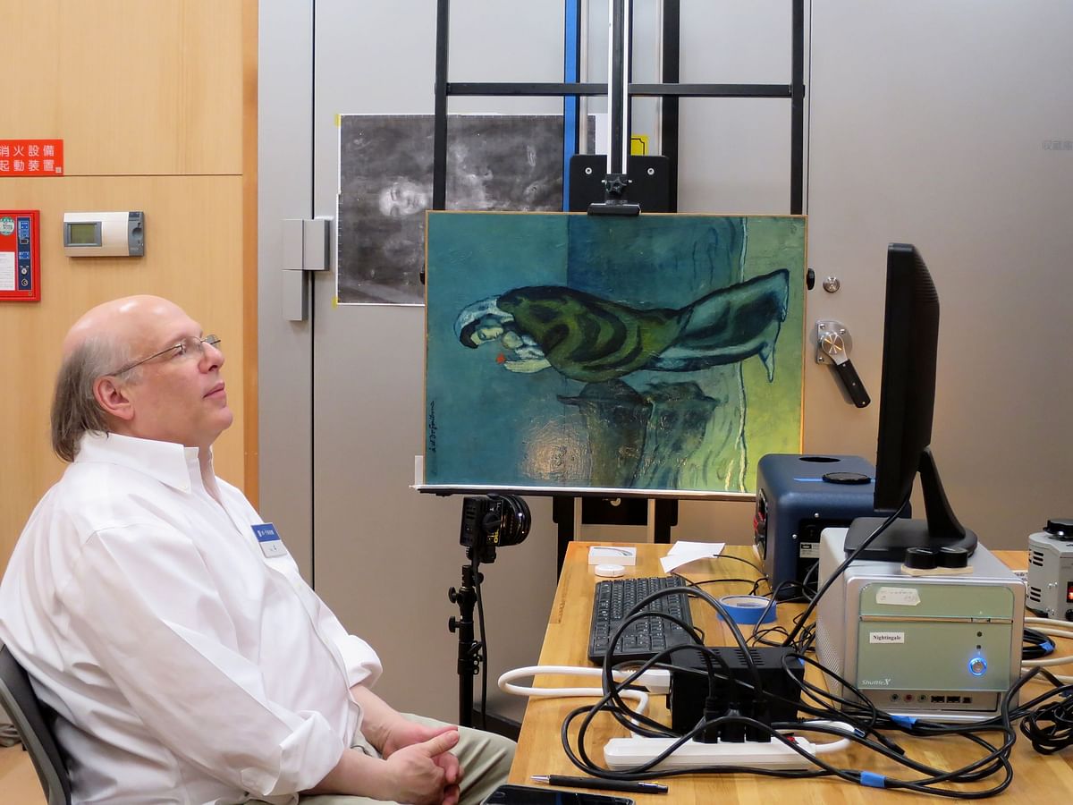This handout picture shows Washington-based National Gallery of Art researcher John Delaney sitting next to the original painting of `Mother and Child by the Sea` by Picasso in 1902, during his research at Pola Museum of Art in Hakone, Kanagawa prefecture. Photo: AFP