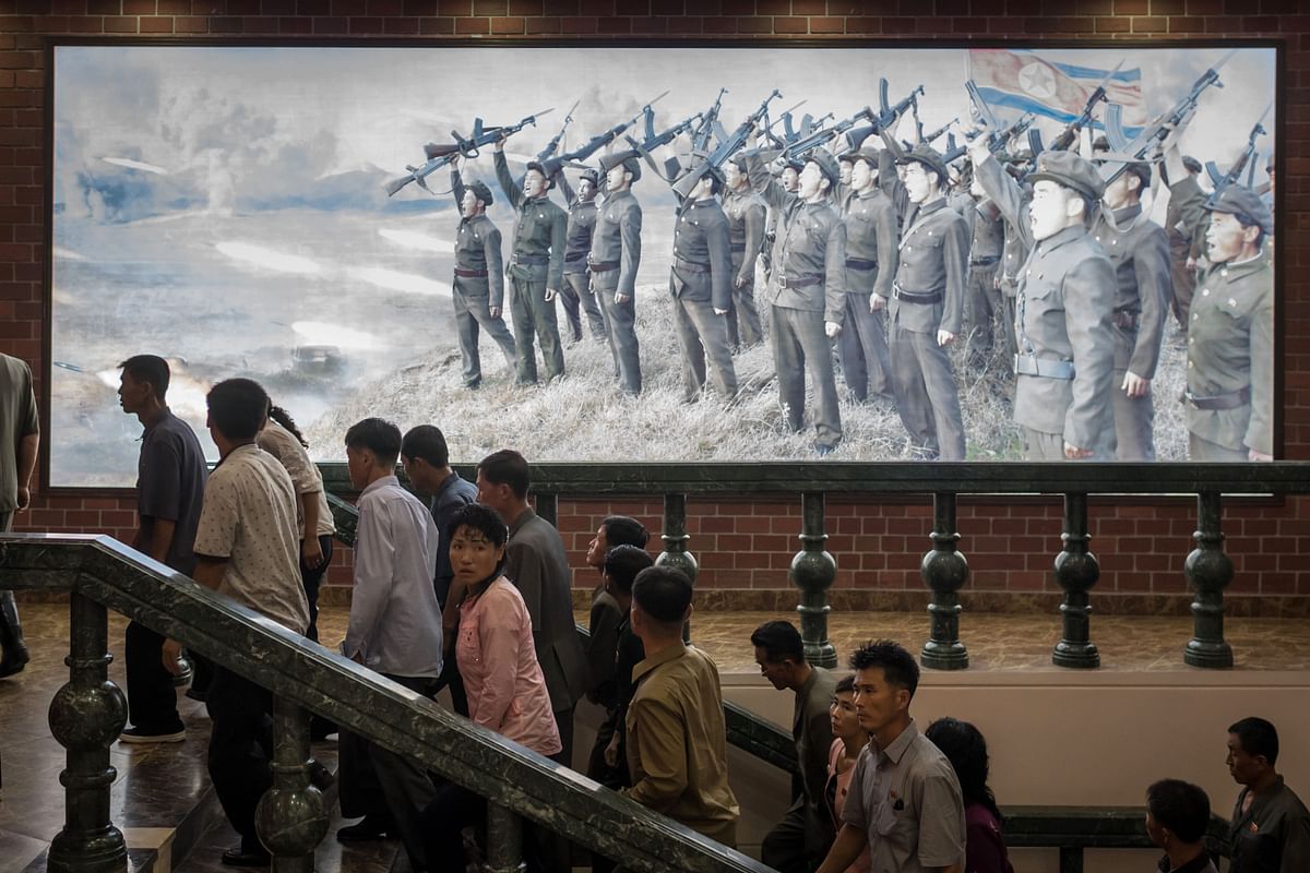 In a file photo taken on 29 July 2017, people walk up stairs before a propaganda poster showing Korean People`s Army (KPA) soldiers at a museum in Sinchon, south of Pyongyang. Photo: AFP
