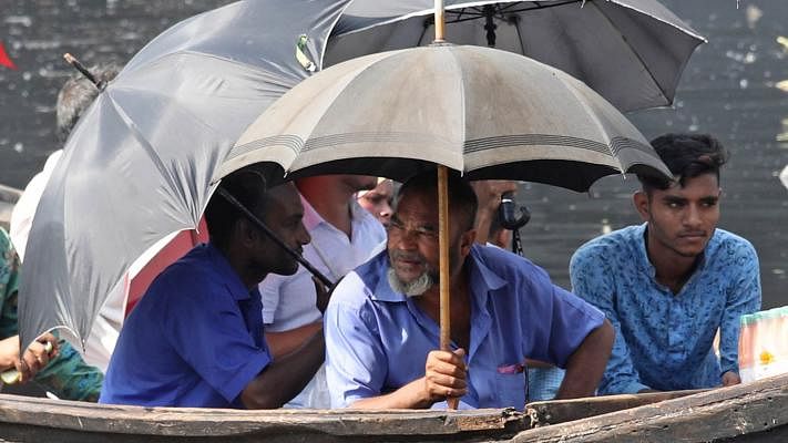 People try to save themselves from the scorching sun with umbrella in the Chaktai canal area near Karnaphuli river, Chattogram on 6 June. Photo: Jewel Shil