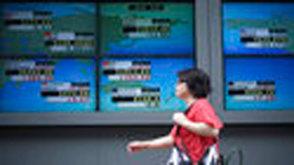 A woman walks past an electronic stock board showing Japan`s Nikkei 225 index and other countries indexes at a securities firm in Tokyo Friday, 8 June, 2018. Asian shares were moderately lower Friday, as investors awaited the Group of Seven leaders` meeting, continuing into the weekend, and for European Central Bank and Federal Reserve meetings next week. Photo : AP