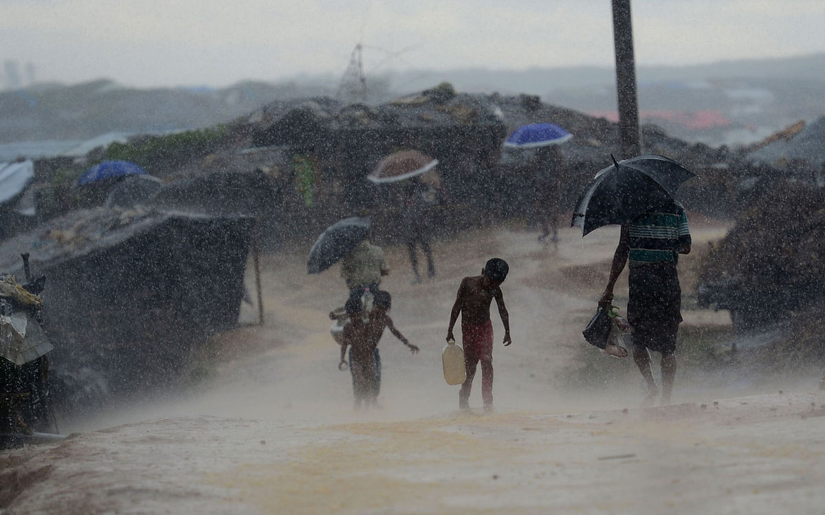 In this file photo taken on 12 October, 2017, a Rohingya refugee child carrries water during rain in a refugee camp at Kutupalong refugee camp in Bangladesh`s Ukhia district. Photo: AFP