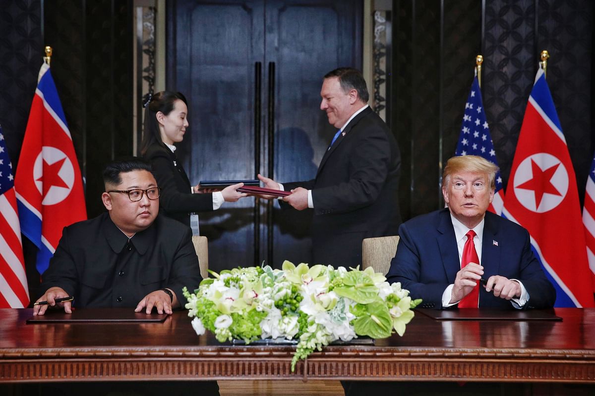 his handout photo taken on 12 June 2018 and released by The Straits Times shows US President Donald Trump (R) and North Korea`s leader Kim Jong Un (L) looking on as documents are exchanged between US Secretary of State Mike Pompeo (2nd R) and the North Korean leader`s sister Kim Yo Jong (2nd L) at a signing ceremony during their historic US-North Korea summit, at the Capella Hotel on Sentosa island in Singapore. Photo: AFP