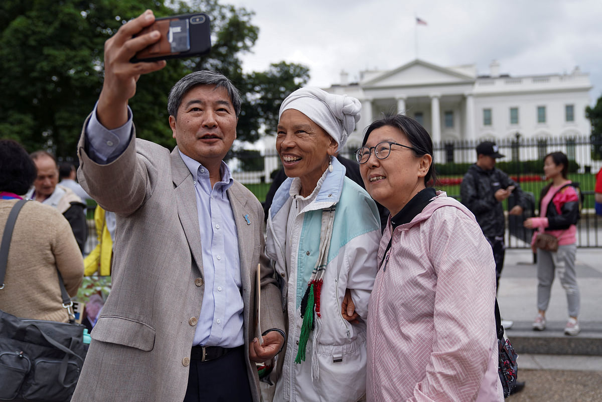 HK Suh, Korean-American, Lucy Murphy and Kate Shim, also Korean-American, take a selfie during a vigil outside the White House to celebrate the joint summit between US president Donald Trump and North Korean leader Kim Jong Un held in Singapore, in Washington, US on 11 June. Photo: Reuters