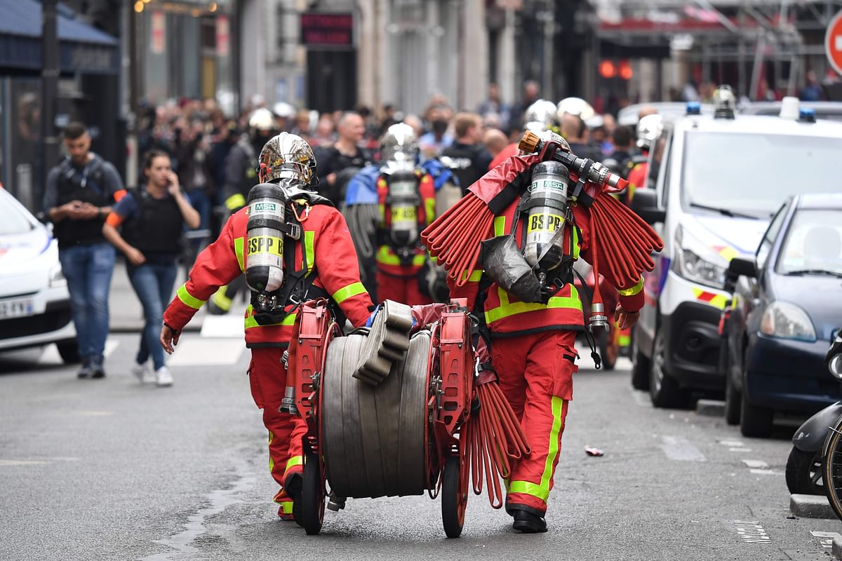 Paris fire brigade firefighters walk with fire hose near the site where an armed man is taking hostages and negotiations with him are underway on 12 June, 2018 in central Paris. Photo: AFP
