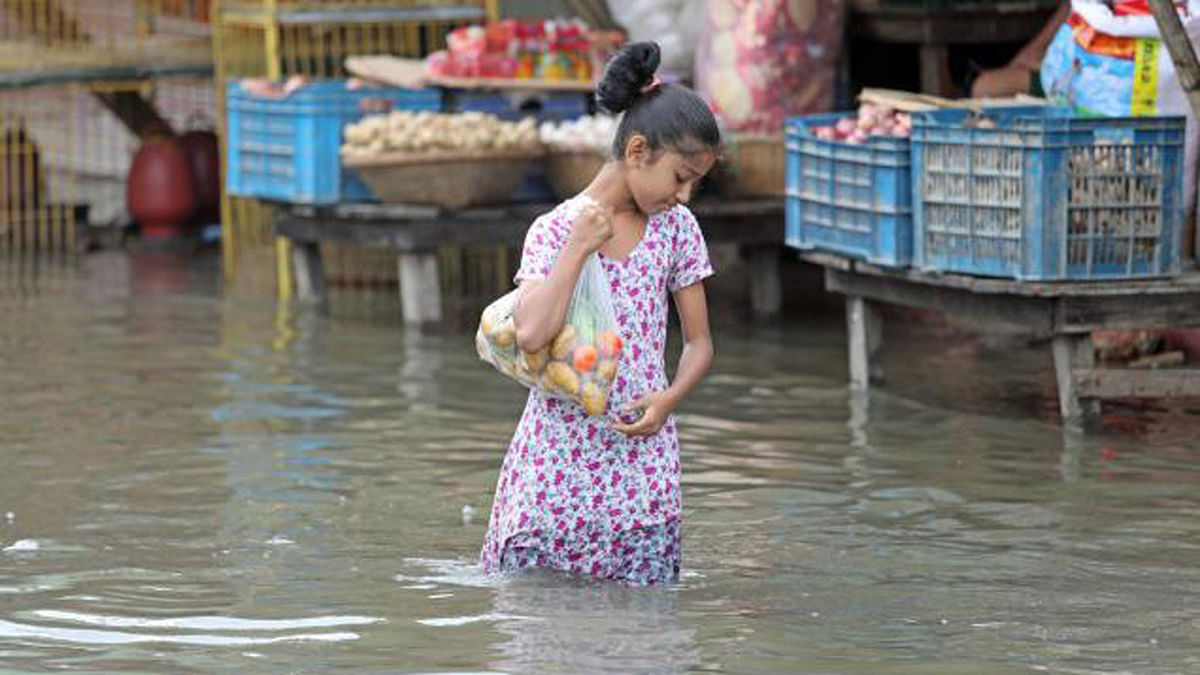 A girl walks with a bag of groceries on a flooded road following a heavy rainfall on Sunday in CDA area of Chattogram. Daily life is heavily hampered due to the excessive rainwater flooding areas in the port city. The photo was taken by Jewel Shil on 11 June