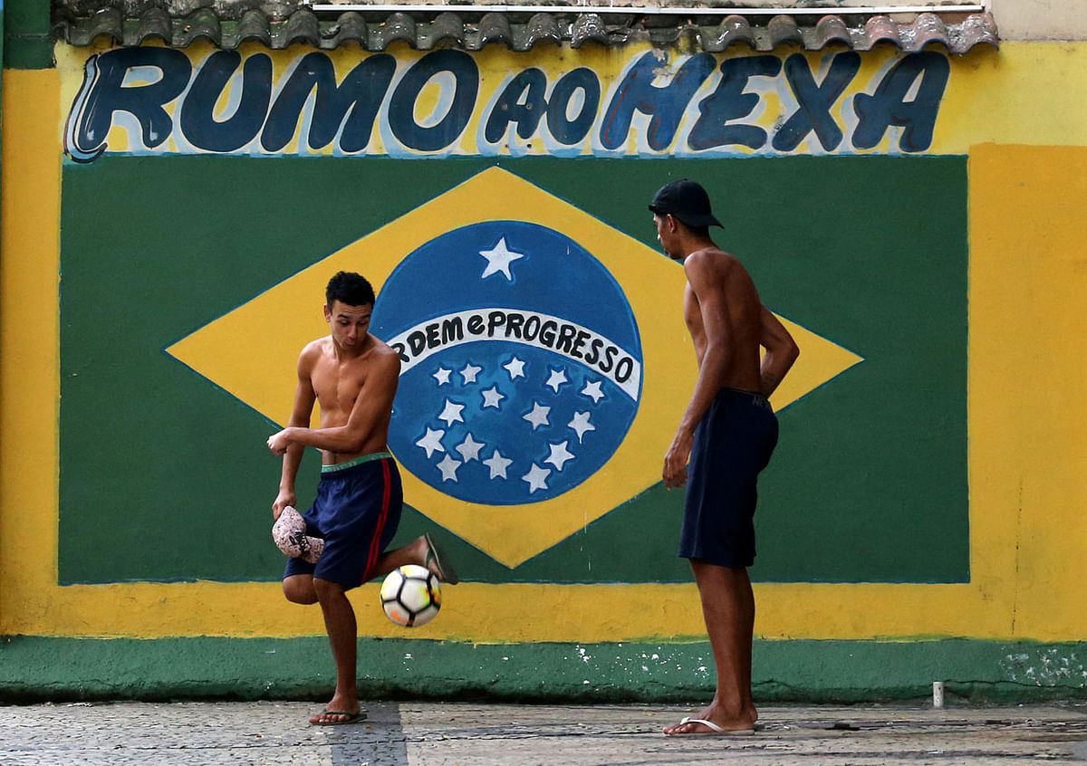 Residents play soccer next to a mural of the Brazilian flag ahead of the 2018 World Cup, at Gloria neighbourhood in Rio de Janeiro, Brazil on 12 June 2018. The sign reads: `Chasing the sixth world title.` Photo: Reuters
