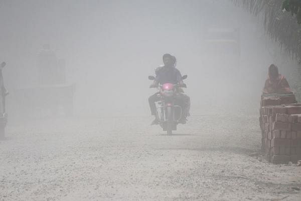 The Ishwardi-Kushtia highway is replete with ruts and holes. The ongoing repair work is inadequate. This is the only route for commuters of 32 districts. A motorcycle crossing the Ishwardi-Kushtia highway in Kushtia through a cloud of dust on 13 June. Photo: Hasan Mahmud.