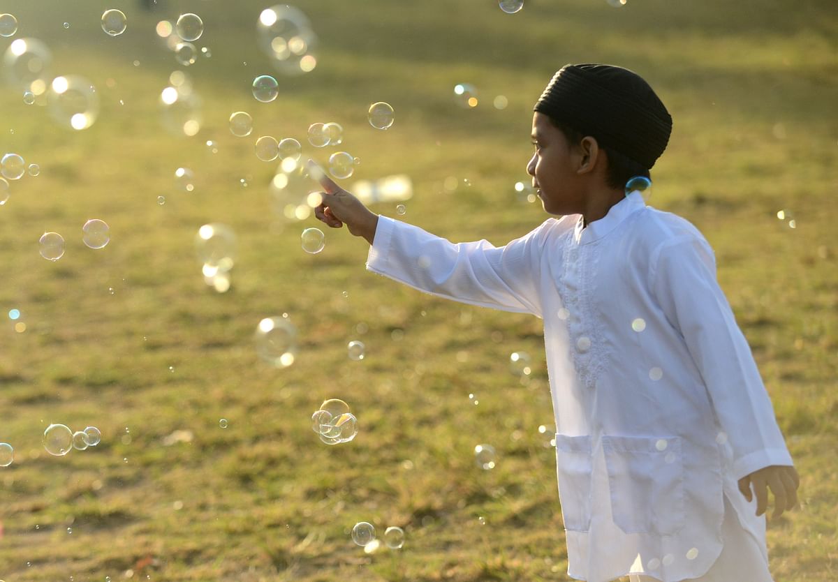 A young boy plays with bubbles as Muslim people take part in a special morning prayer celebrating Eid al-Fitr festival at Bali`s Bajra Sandhi monument and park in Denpasar on 15 June 2018. Photo: AFP