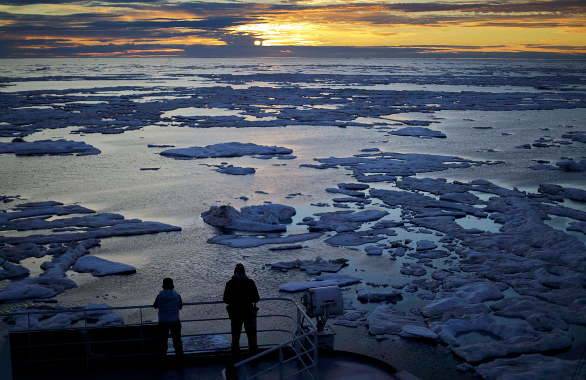 In this 21July, 2017 file photo, researchers look out from the Finnish icebreaker MSV Nordica as the sun sets over sea ice in the Victoria Strait along the Northwest Passage in the Canadian Arctic Archipelago. Studies show the Arctic is heating up twice as fast as the rest of the planet. Scientists are concerned because impacts of a warming Arctic may be felt elsewhere. Photo : AP